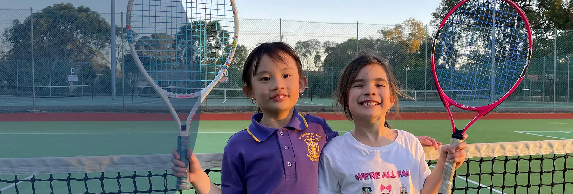 Two young girls enjoying a tennis lesson